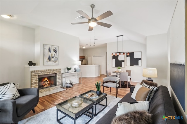 living area featuring ceiling fan, wood finished floors, lofted ceiling, and a fireplace
