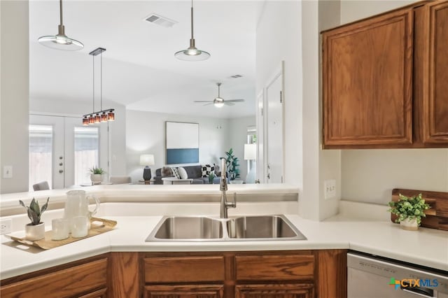 kitchen featuring dishwasher, a sink, brown cabinets, and plenty of natural light