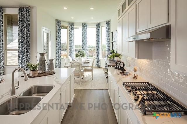 kitchen featuring a sink, plenty of natural light, stainless steel gas cooktop, and under cabinet range hood
