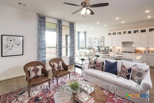 living room featuring visible vents, wood finished floors, baseboards, ceiling fan, and recessed lighting