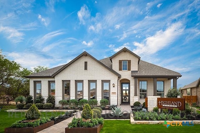 back of property featuring a yard and brick siding