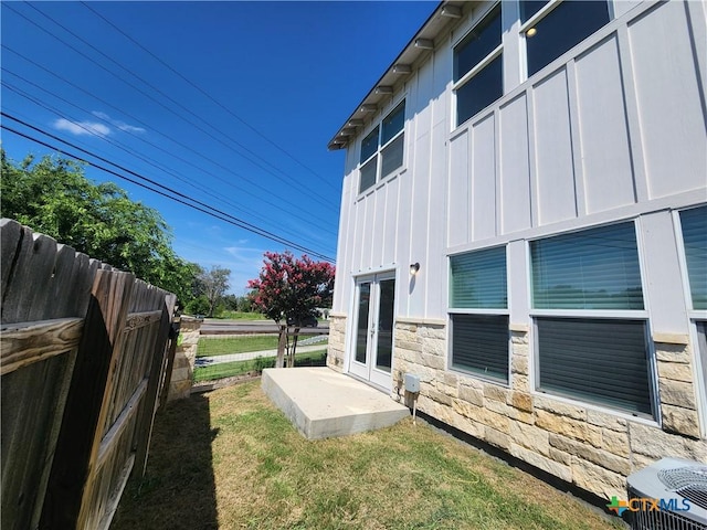 view of yard featuring french doors, central AC unit, and fence