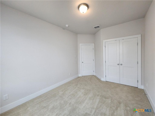 unfurnished bedroom with a closet, visible vents, carpet flooring, and baseboards