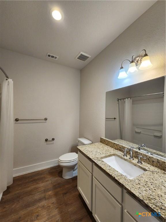 full bath with visible vents, baseboards, toilet, and wood finished floors