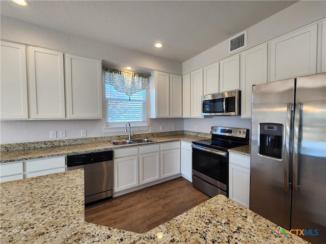 kitchen with visible vents, a sink, stainless steel appliances, white cabinets, and light stone countertops