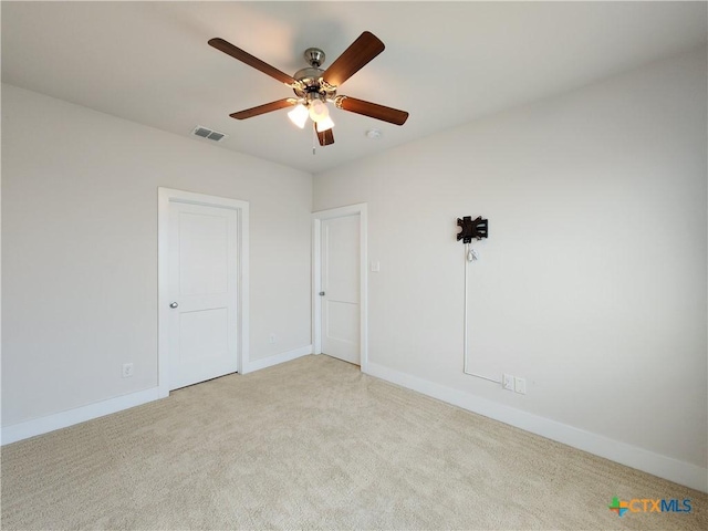 empty room with visible vents, baseboards, light colored carpet, and ceiling fan