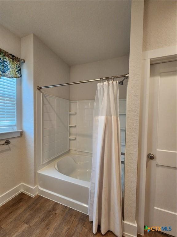 full bathroom featuring baseboards, shower / bath combo with shower curtain, a textured ceiling, and wood finished floors