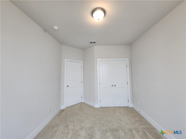 unfurnished bedroom with baseboards, visible vents, carpet floors, a closet, and a textured ceiling