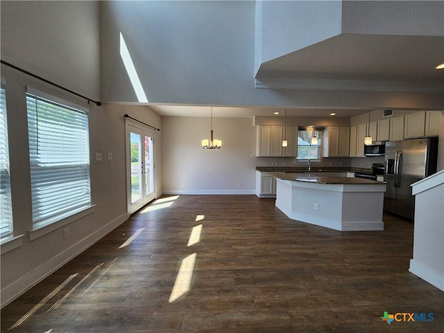 kitchen featuring dark countertops, a center island, french doors, appliances with stainless steel finishes, and baseboards