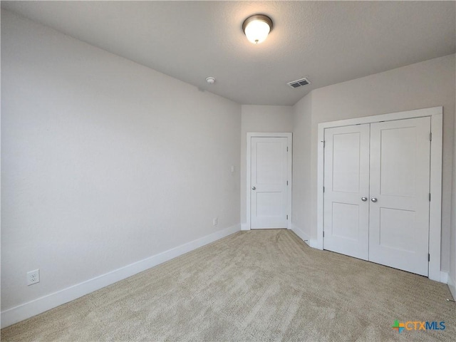 unfurnished bedroom with carpet, baseboards, visible vents, a closet, and a textured ceiling