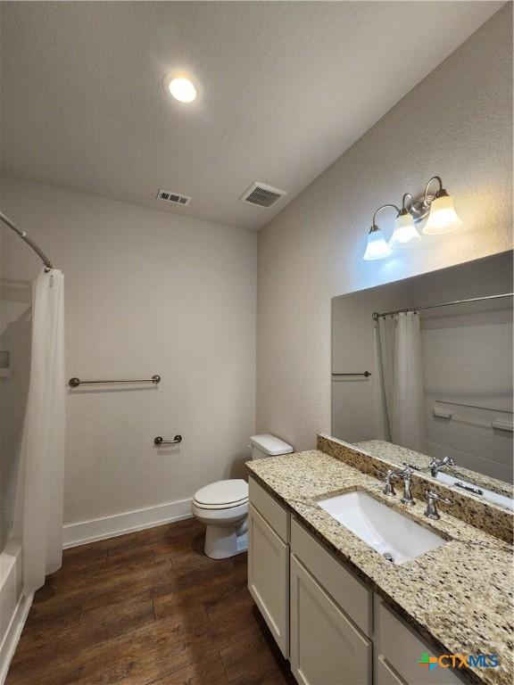 bathroom featuring visible vents, baseboards, toilet, and wood finished floors