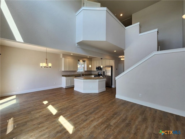 kitchen featuring dark countertops, appliances with stainless steel finishes, open floor plan, and dark wood-style flooring