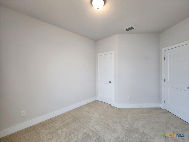 unfurnished room with baseboards, visible vents, and light carpet