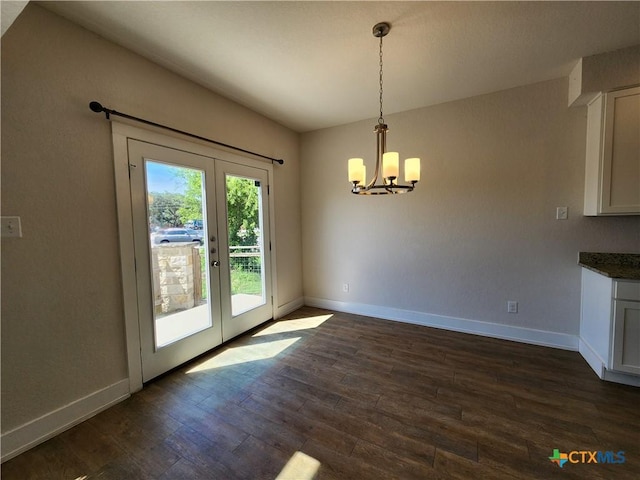 unfurnished dining area with an inviting chandelier, french doors, dark wood-style flooring, and baseboards