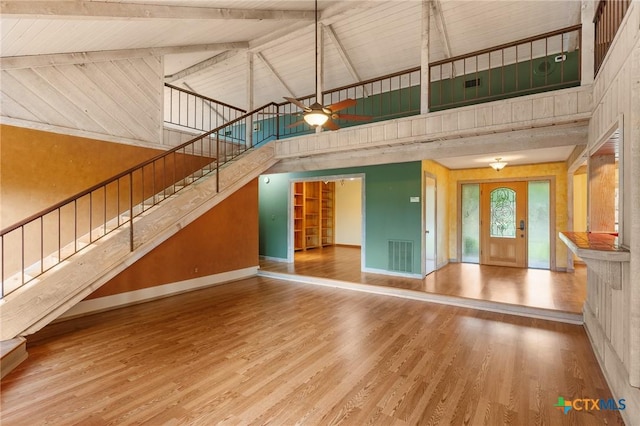 2820 Aurora, Horseshoe Bay, TX 78657 - unfurnished living room featuring high vaulted ceiling, stairway, ceiling fan, wood finished floors, and wood walls