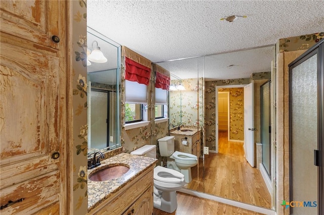 2820 Aurora, Horseshoe Bay, TX 78657 - full bath featuring a textured ceiling, wood finished floors, a shower stall, vanity, and wallpapered walls