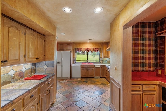 2820 Aurora, Horseshoe Bay, TX 78657 - kitchen with white appliances, stone tile flooring, tile counters, decorative backsplash, and recessed lighting