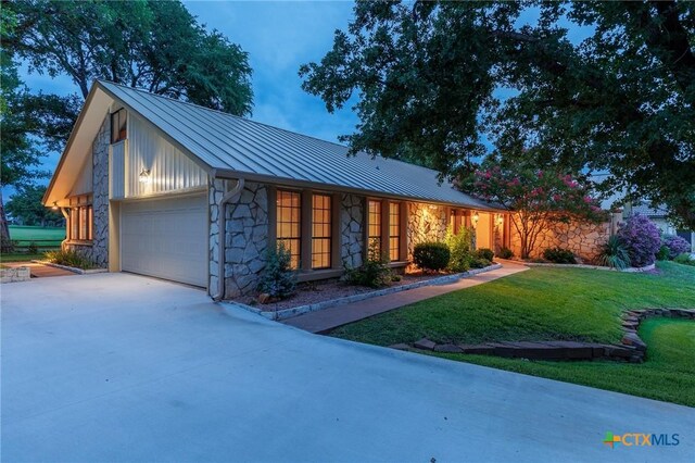 2820 Aurora, Horseshoe Bay, TX 78657 - view of front of home featuring stone siding, a standing seam roof, a front lawn, an attached garage, and concrete driveway