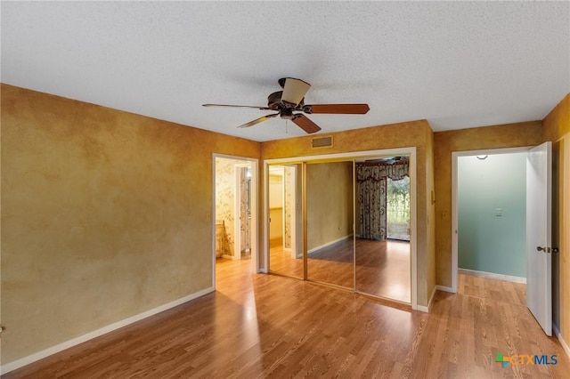 2820 Aurora, Horseshoe Bay, TX 78657 - unfurnished bedroom with light wood-type flooring, a closet, a ceiling fan, and a textured ceiling