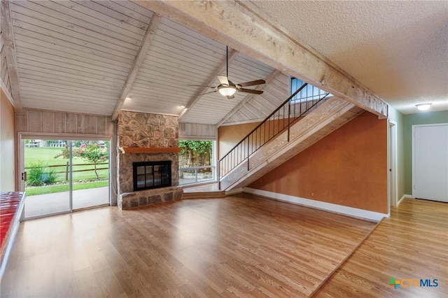 2820 Aurora, Horseshoe Bay, TX 78657 - unfurnished living room with wood finished floors, a ceiling fan, stairway, a fireplace, and a textured ceiling
