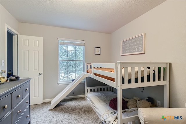 bedroom with light colored carpet and a textured ceiling