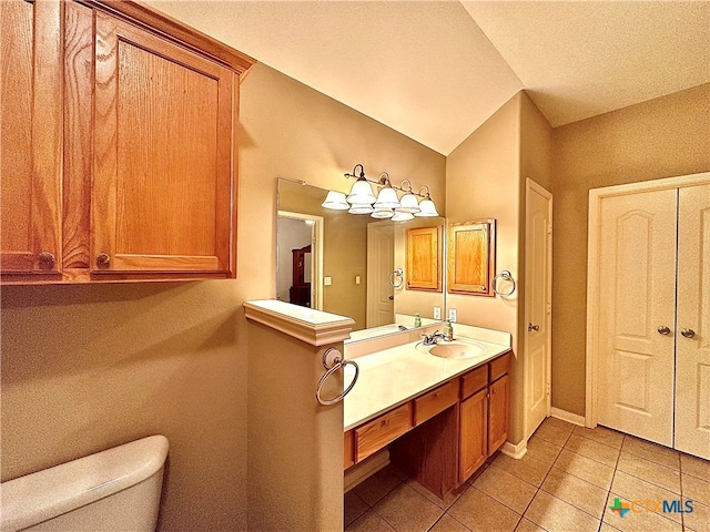 bathroom with tile patterned floors, vanity, a textured ceiling, vaulted ceiling, and toilet