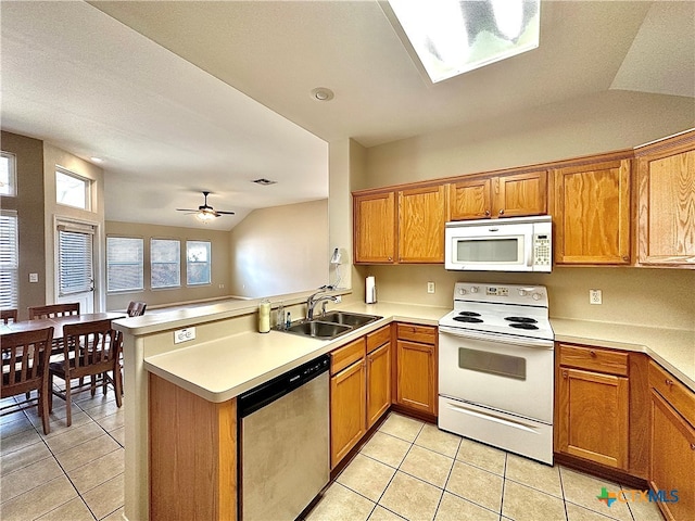 kitchen featuring vaulted ceiling, kitchen peninsula, sink, light tile patterned floors, and white appliances