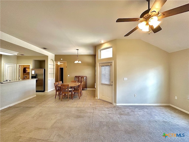 dining area featuring vaulted ceiling, light colored carpet, and ceiling fan with notable chandelier