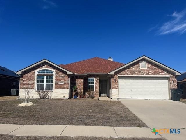 ranch-style house with an attached garage, concrete driveway, and brick siding