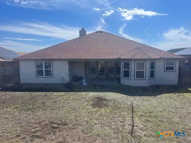 2107 Golden Eagle Dr, Killeen, TX 76549 - rear view of property with a shingled roof, fence, a lawn, stucco siding, and a chimney