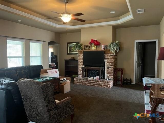 2107 Golden Eagle Dr, Killeen, TX 76549 - carpeted living room featuring a brick fireplace, visible vents, a tray ceiling, and arched walkways