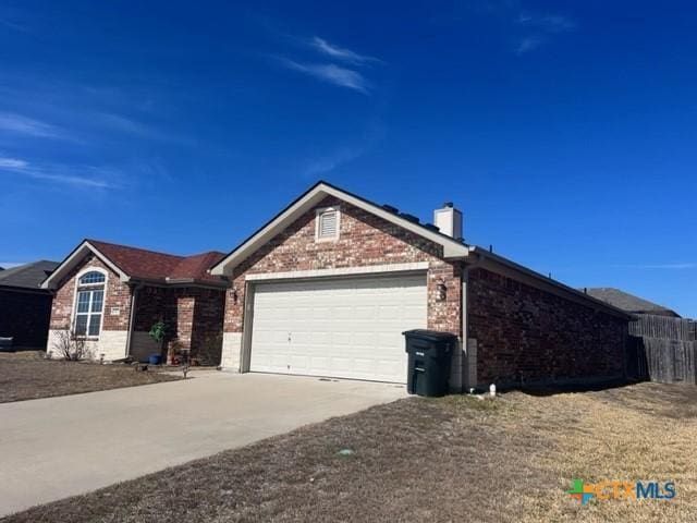 ranch-style house with an attached garage, a chimney, concrete driveway, and brick siding