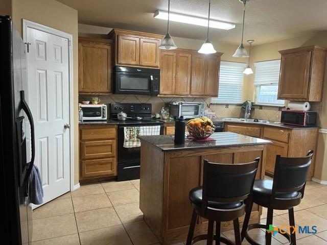 2107 Golden Eagle Dr, Killeen, TX 76549 - kitchen with dark countertops, backsplash, light tile patterned flooring, a sink, and black appliances