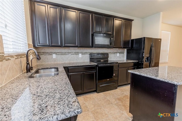 kitchen featuring black appliances, tasteful backsplash, dark brown cabinets, sink, and light stone counters