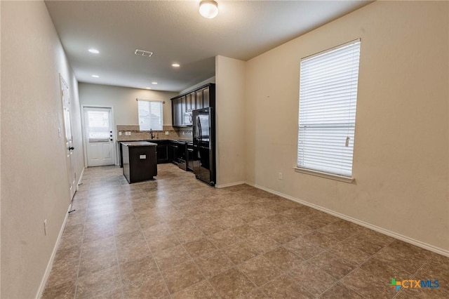 kitchen with sink, black fridge, a center island, and tasteful backsplash