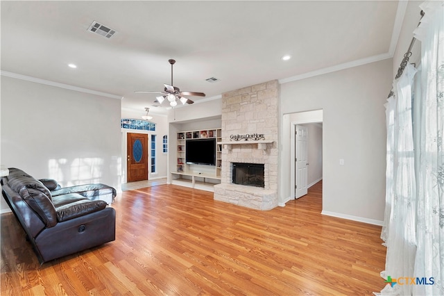 living room featuring crown molding, light hardwood / wood-style flooring, ceiling fan, built in shelves, and a fireplace