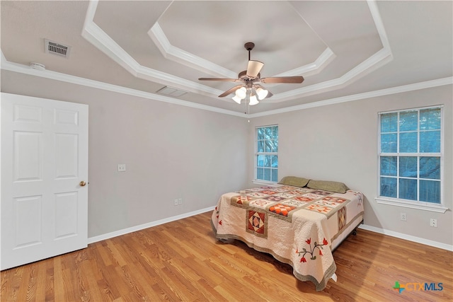 bedroom featuring a tray ceiling, ceiling fan, crown molding, and light hardwood / wood-style floors