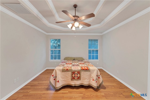 bedroom with ceiling fan, wood-type flooring, crown molding, and a tray ceiling