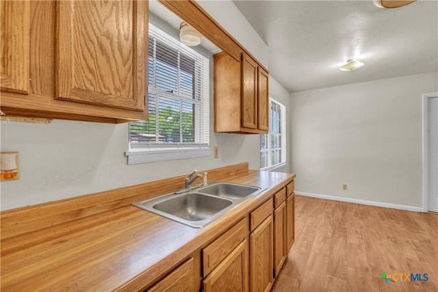 1210 Ridgemont Dr, Killeen, TX 76549 - kitchen featuring a sink, light countertops, light wood-style floors, brown cabinetry, and baseboards