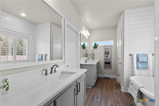 117 Aidan Ct, Burnet, TX 78611 - full bathroom featuring two vanities, a bathtub, wood finished floors, and baseboards