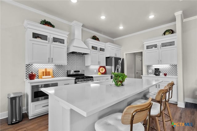 117 Aidan Ct, Burnet, TX 78611 - kitchen featuring appliances with stainless steel finishes, custom range hood, light countertops, tasteful backsplash, and a breakfast bar