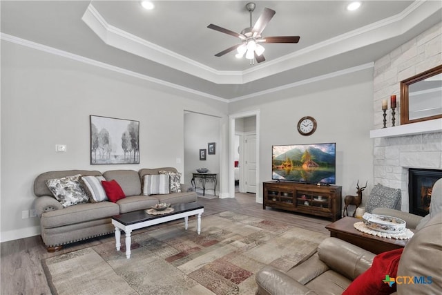 117 Aidan Ct, Burnet, TX 78611 - living room featuring ceiling fan, a tray ceiling, wood finished floors, crown molding, and a stone fireplace