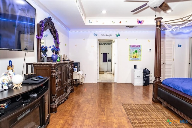 bedroom with a tray ceiling, wood finished floors, and ornamental molding