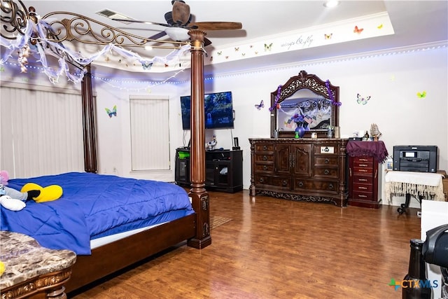 bedroom with a tray ceiling, ornamental molding, and dark wood-style flooring