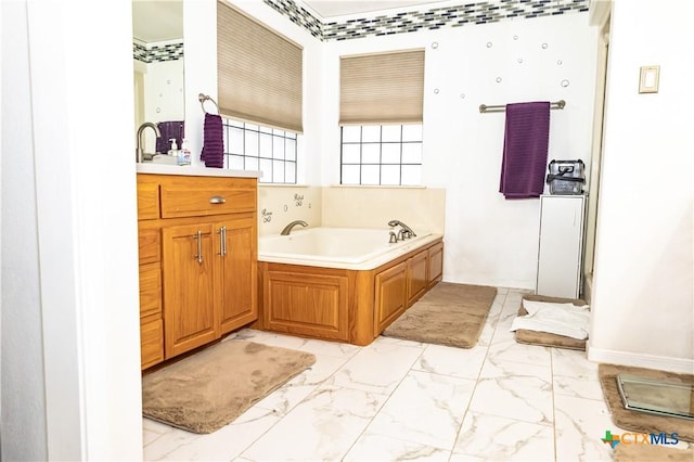 bathroom with marble finish floor, a garden tub, and vanity