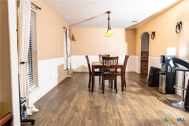 dining area with arched walkways, wood finished floors, and visible vents