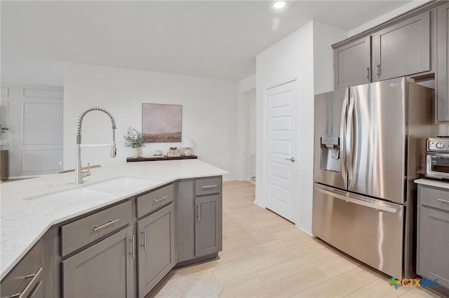 4648 Padula Dr, Round Rock, TX 78665 - kitchen featuring stainless steel fridge with ice dispenser, gray cabinetry, light stone countertops, light wood-type flooring, and recessed lighting