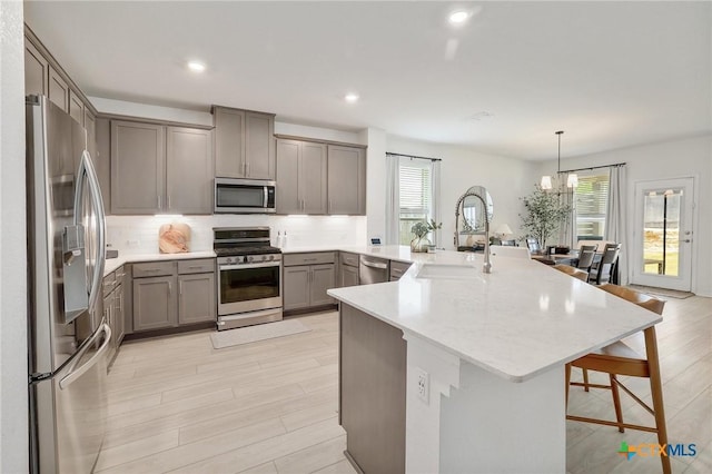 4648 Padula Dr, Round Rock, TX 78665 - kitchen with stainless steel appliances, gray cabinetry, a breakfast bar area, a peninsula, and backsplash