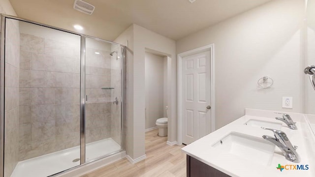 bathroom featuring walk in shower, vanity, toilet, and hardwood / wood-style flooring