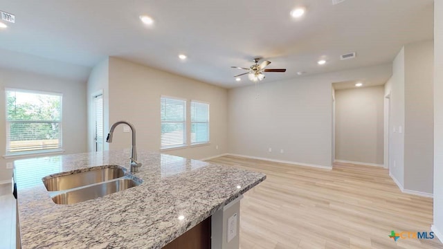 kitchen with sink, light stone countertops, light hardwood / wood-style floors, and ceiling fan